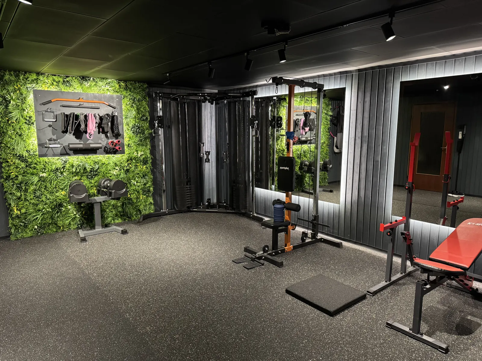 Fitness Showroom mit Trainingsfläche, Kabelzug, Spiegeln und Pflanzenwand